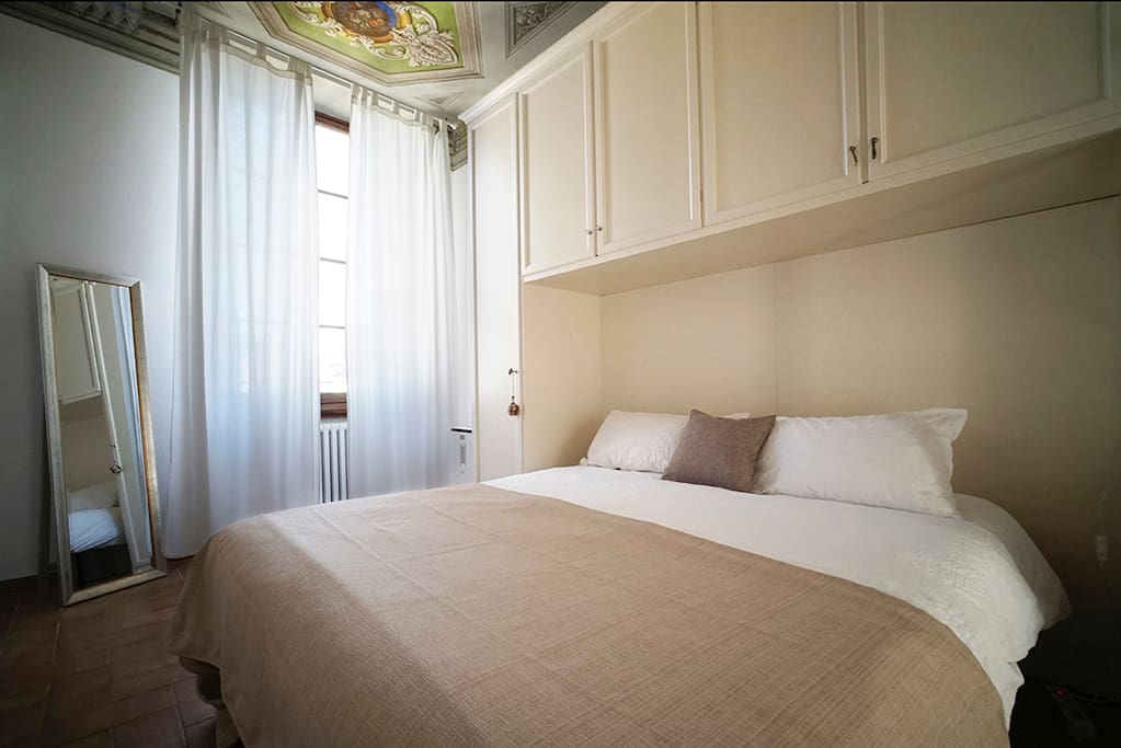 Queen bed with view of terracotta rooftops