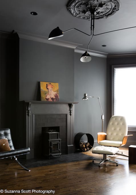 The living room features a bay window, artbooks and novels for the bookworms, and a working wood-burning stove.