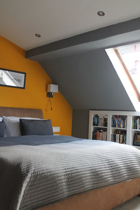 Spacious bedroom with a superking bed, floating shelves either side of the bed and a mini library.