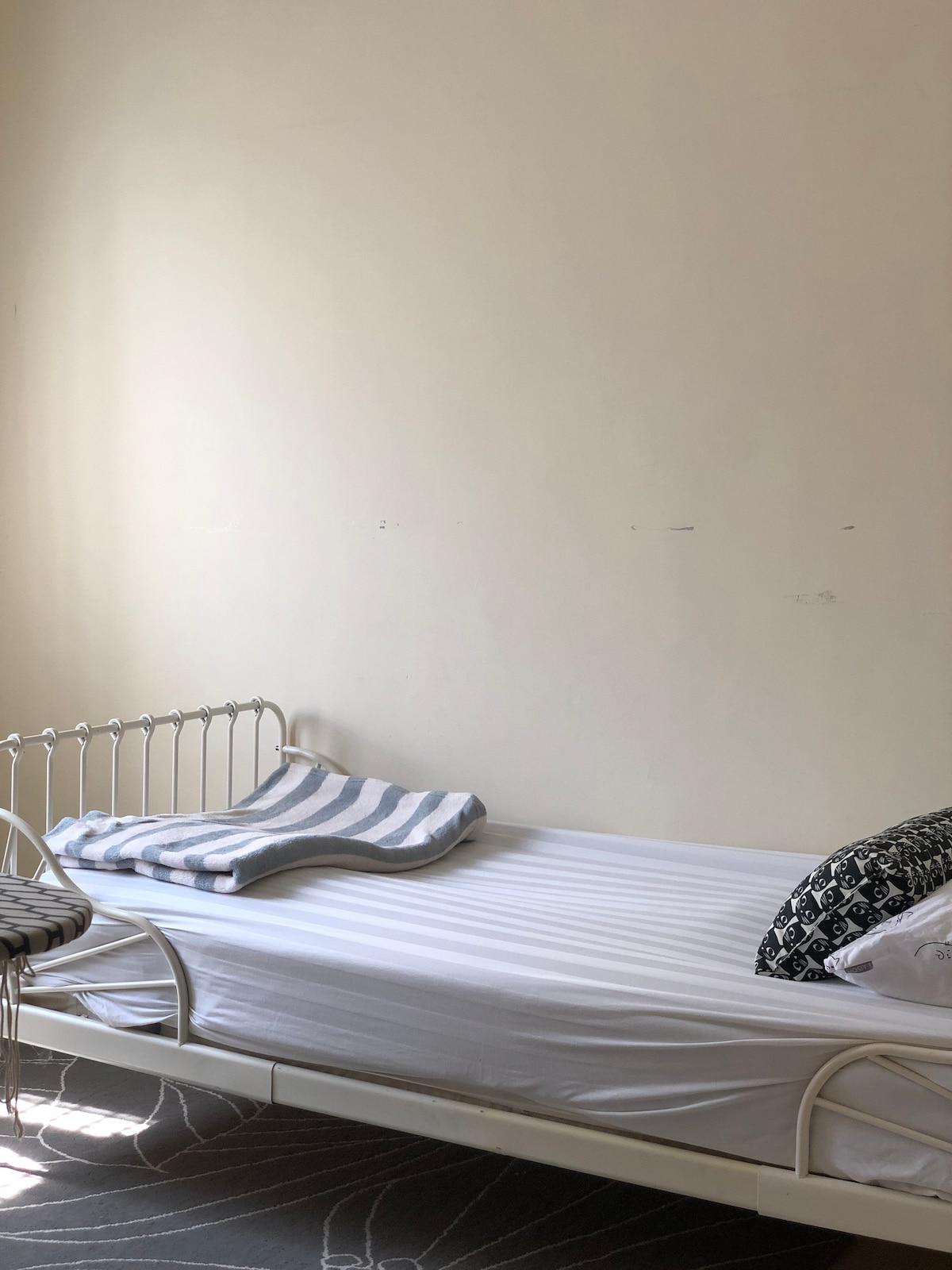 Cuarto dormitorio equipado con cama individual y ventilador de techo y soporte de espejo. También se proporcionó plancha con tabla y soporte para colgar tu vestido.