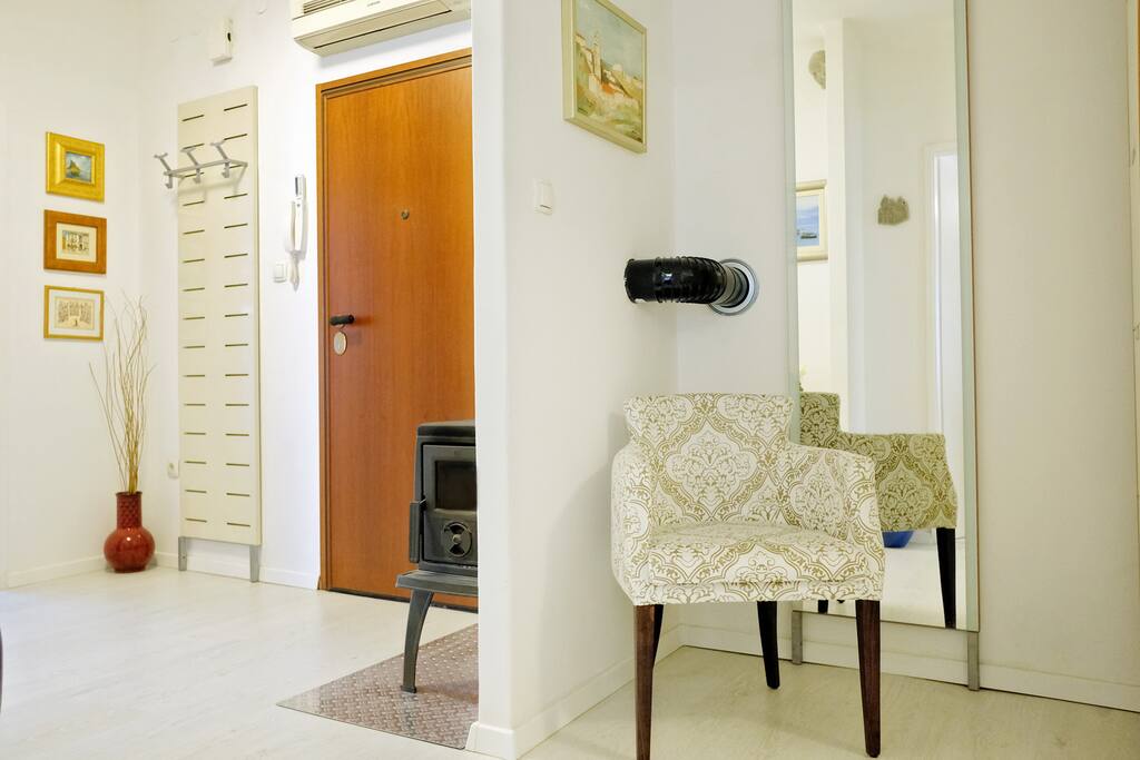 Spacious foyer with a big mirror and a comfy chair