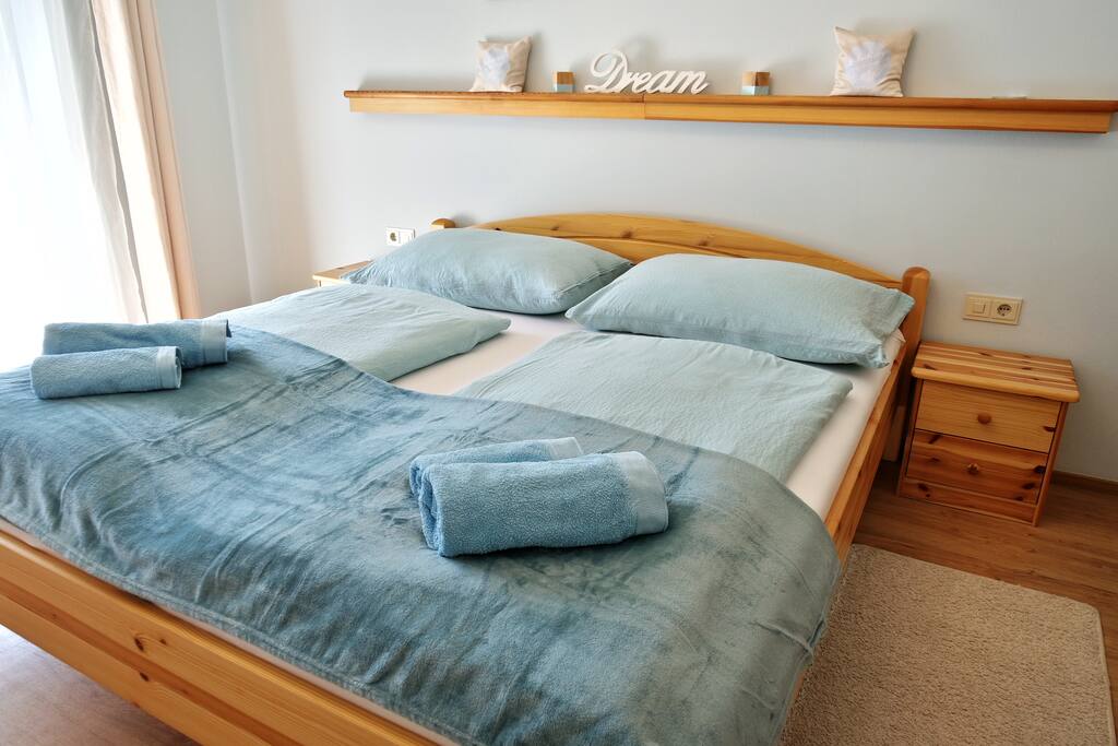 Ein großzügiges Doppelbett aus Kiefernvollholz lädt zum Entspannen und Kuscheln ein.