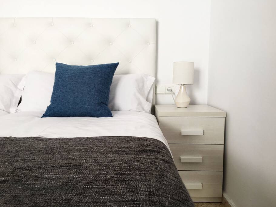 El dormitorio con mesilla de noche y lámpara al lado de cada cama.