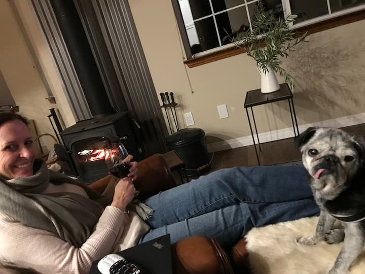 Vaša hostiteľka relaxuje pred krbom na drevo so psom. 