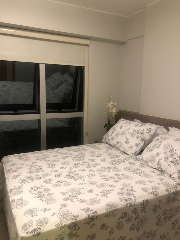 Suite com cama de casal com a cortina levantada.