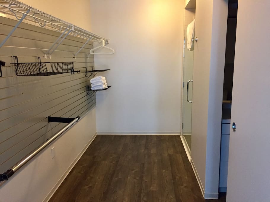 Huge walk-in closet connected to shower with towels and bath mats. There is a door separating the bedroom and this space.