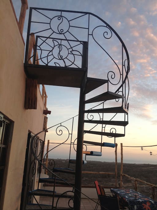 view of sunset from second story patio w/ stairs going to roof deck.