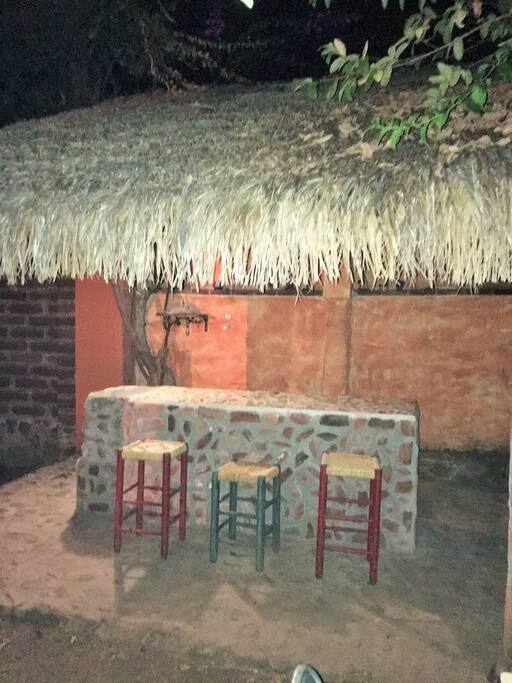 Palapa con asador y barra de bar.