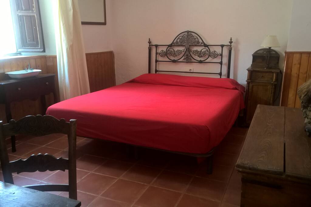 Habitación luminosa con cama XXL y colchón de látex.
Contiene un armario grande, varios baúles de madera y un escritorio pequeño.