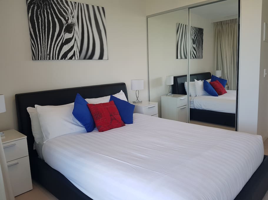 Queen bed with ceiling fan and glass sliding door opening onto balcony.