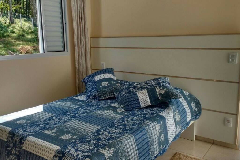 Cama confortável com roupa de cama e travesseiros inclusos no quarto. vista para as araucárias.