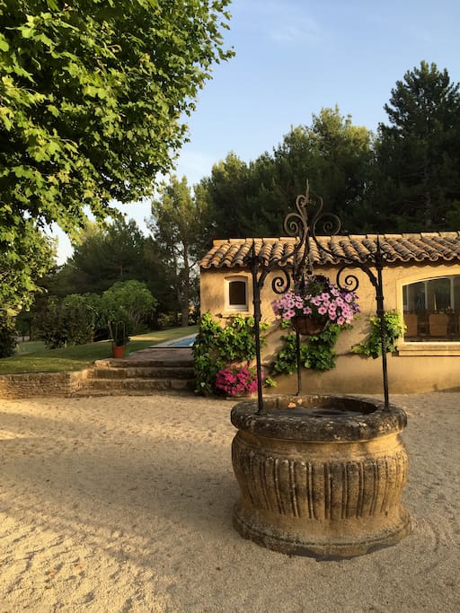 Pool house and pool with well in foreground on gravel terrace.