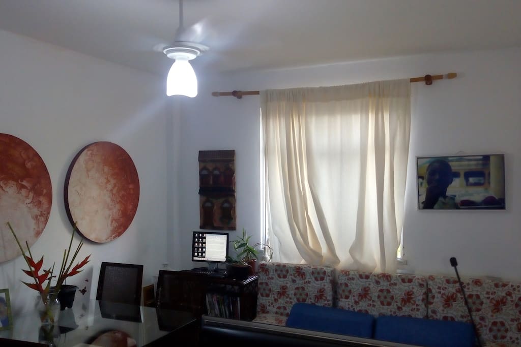 outro ângulo da sala, janela com visão para a área externa com algumas árvores e plantas.