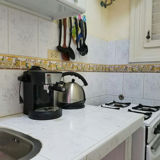 Cocina completamente equipada con cafetera, hervidor de agua, vajilla, horno, microwave y refrigerador.
