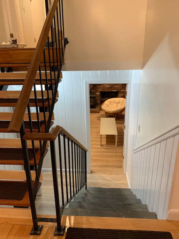 ფართო საოჯახო ოთახისკენ მიმავალი კიბეები ორი ფუტლიარით და აბაზანა-ტუალეტით