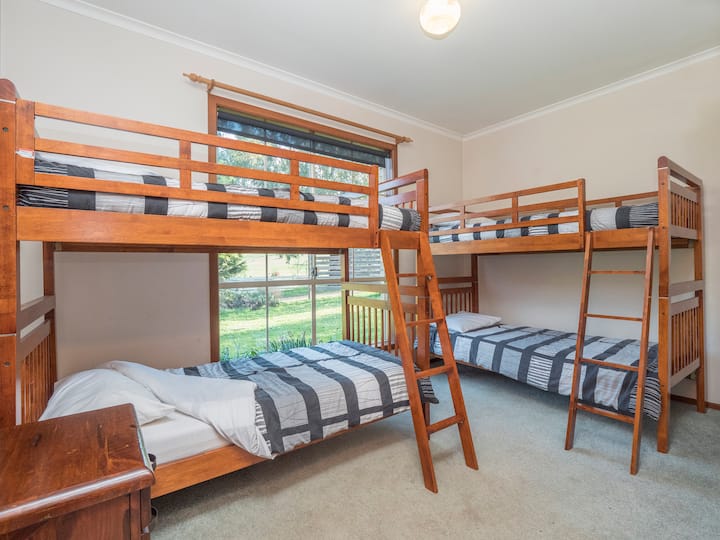 Tercer dormitorio Hillview, con 4 literas individuales: lámpara, mesita de noche y ventilador de pedestal