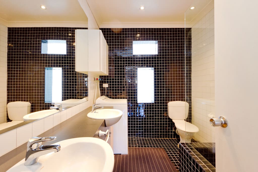 Sparkling central bathroom with twin vanity basins, bath, shower and washing machine.