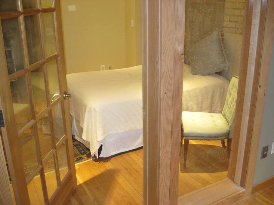 Bedroom features full size bed, wood floor, hotel quality linens, tv, ceiling fan, radio and night stand