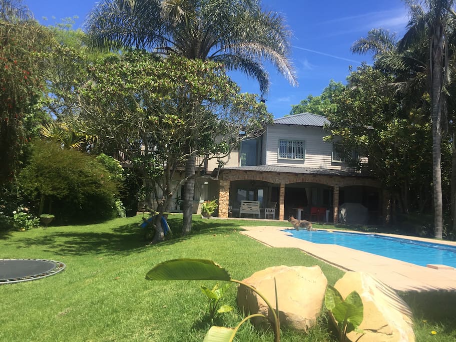 Front view of house, garden, patio, swimming pool and trampoline.