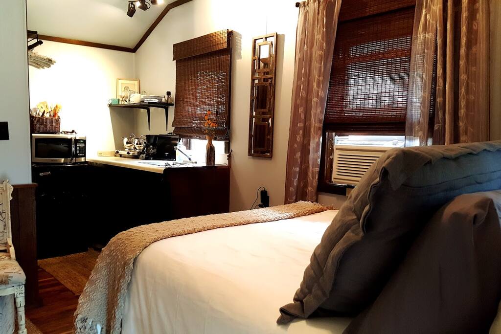 The open floor plan of the room offers a queen bed, a small sitting area and kitchenette.