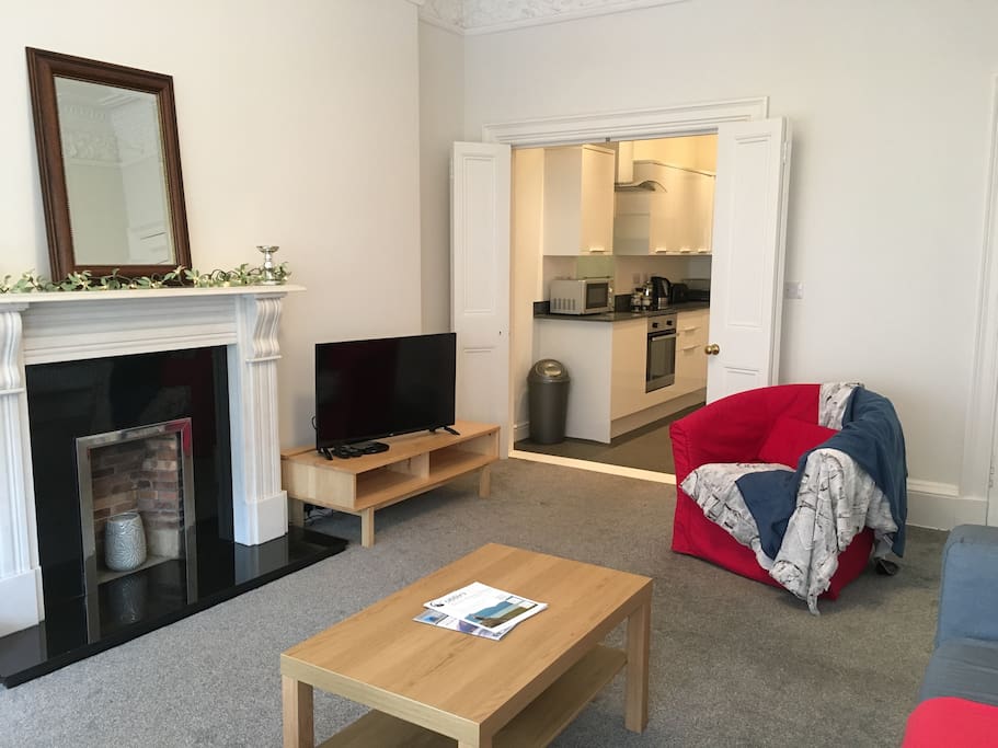 Living room with feature fireplace, TV, sofa, armchair.