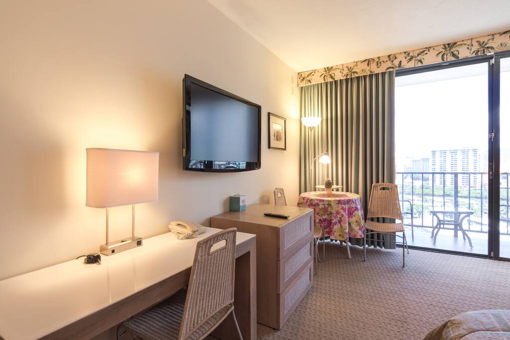 The living area includes a desk space, table and chairs, TV, and dresser.
