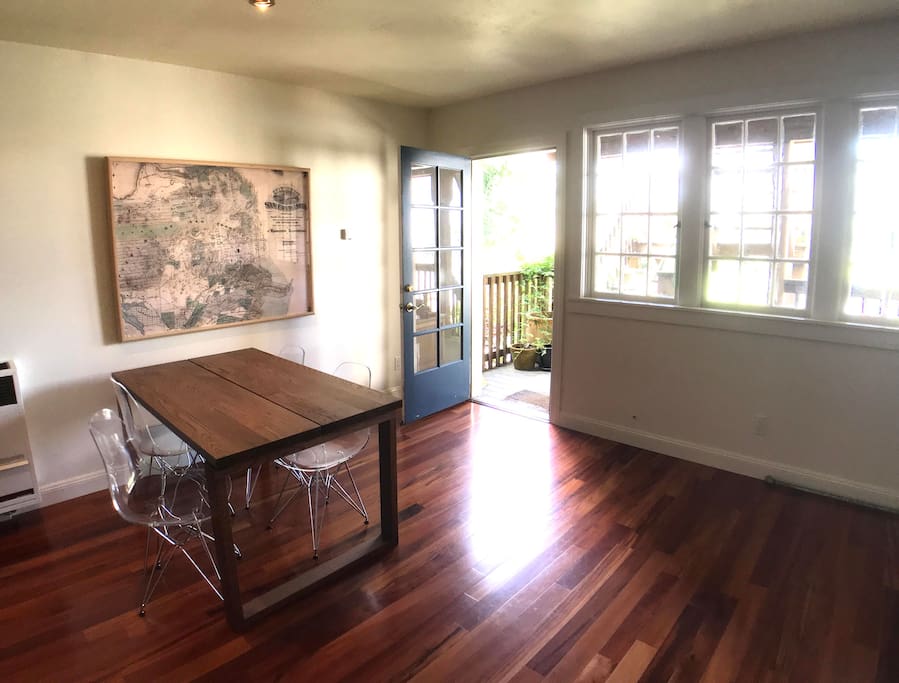Large dining area with seating and settings for four, door and windows to deck