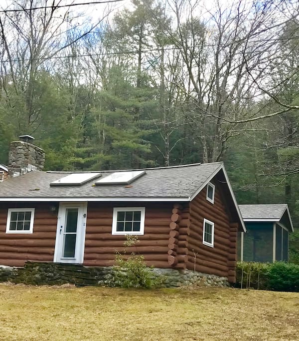 Large screened porch behind the log cabin.
