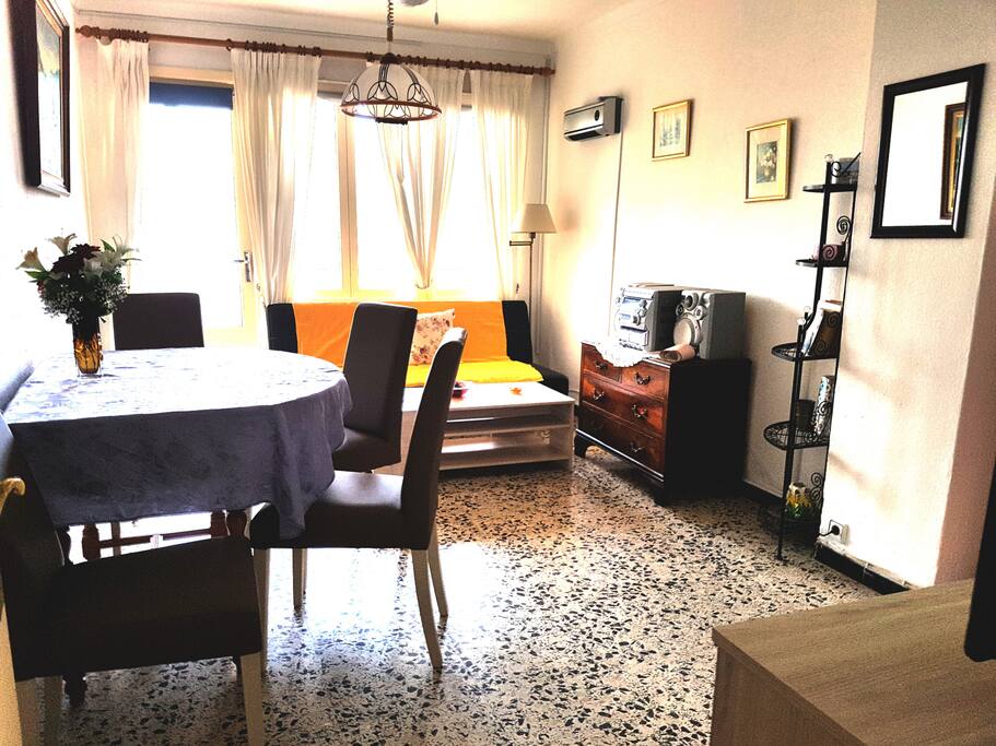 Wohnzimmer mit Esstisch, Fernseher, Schlafcouch und Zugang zum Südbalkon