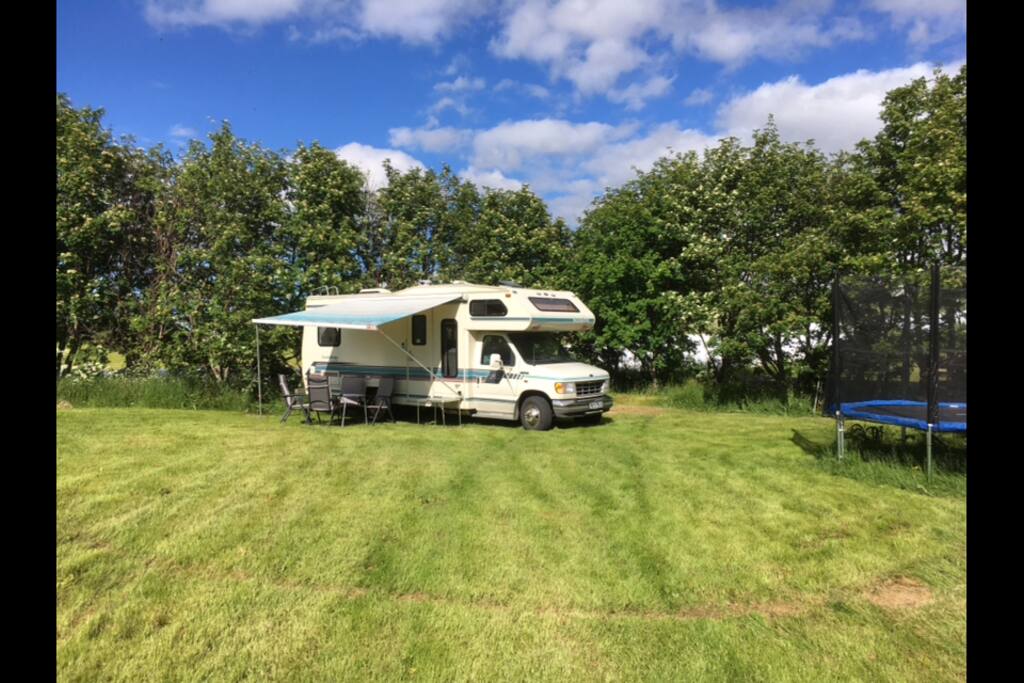 Bobilen står på gressplen utenfor vårt hjem.