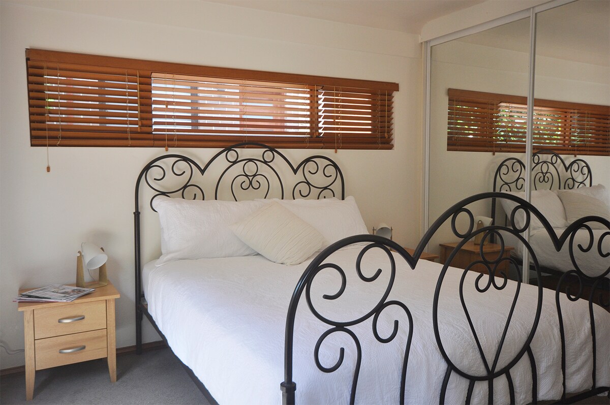 Dormitorio privado lleno de luz en la planta baja con puertas de armario con espejos.