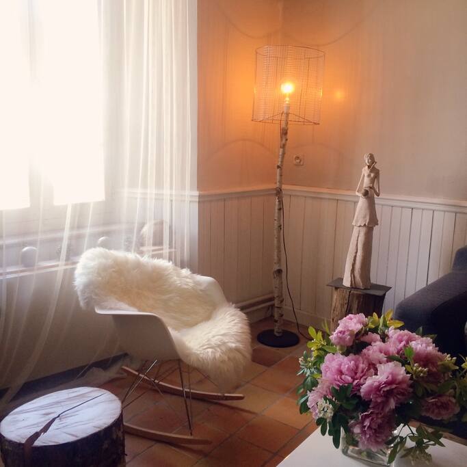 Dans la salle de vie , un rocking chair inspiré de Charles Eames est recouvert d'une peau de mouton, lampadaire d'une jeune créatrice Toulousaine, sculpture en terre cuite