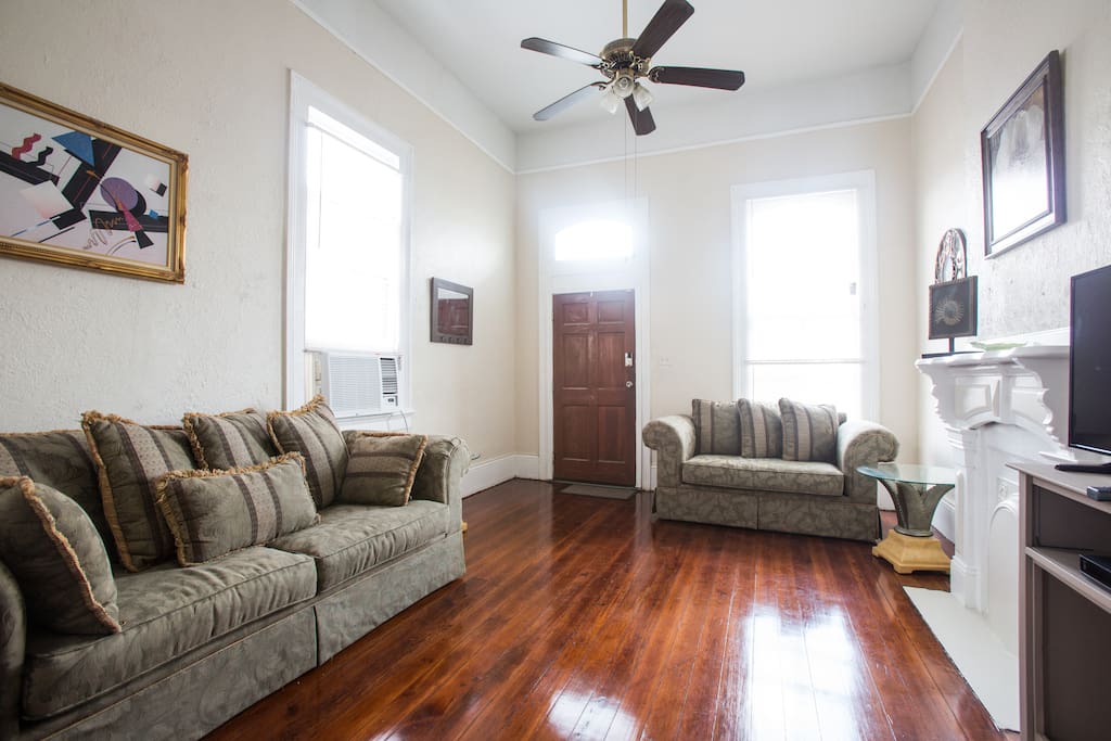 Front entrance to a large living room with sofa and love seat. TV with cable and internet hook up.