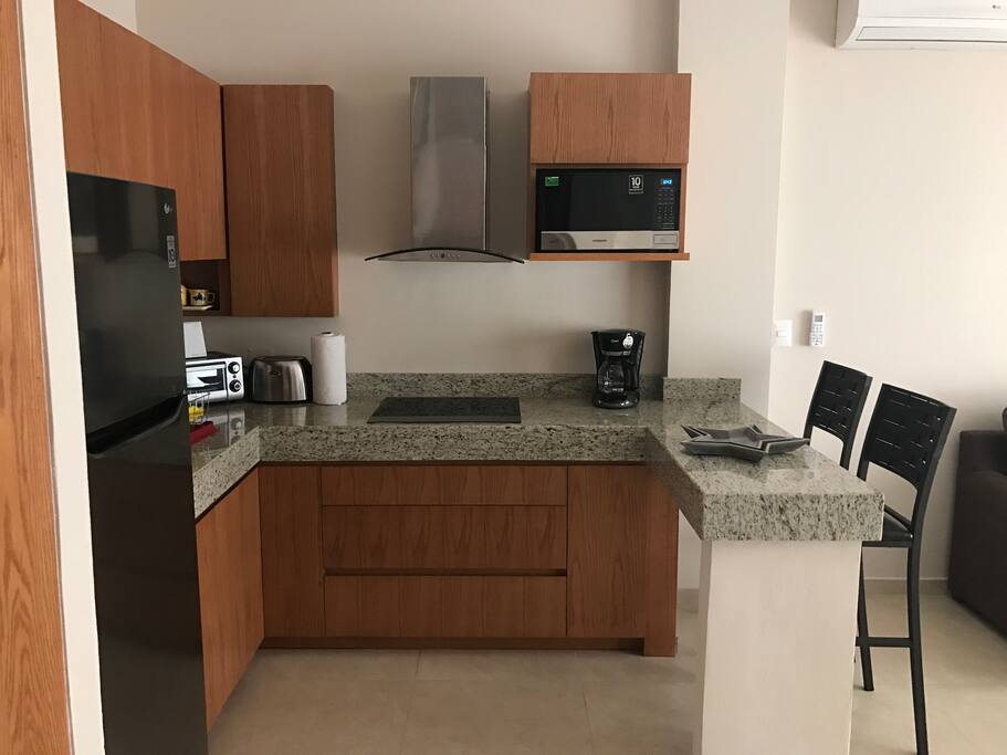 A complete integrated kitchen with a comfortable counter top for seating.