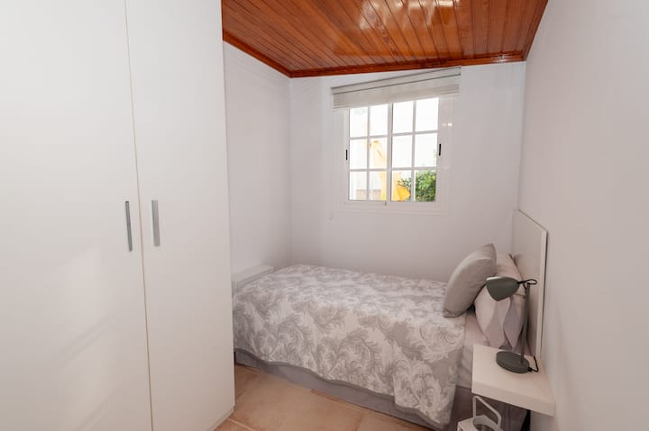 habitación luminosa, llena de luz y brillo fuerte. Es cómodo y acogedor, lo que le da una sensación de calidez. Las  ventanas tienen una cortina de tela blanca.