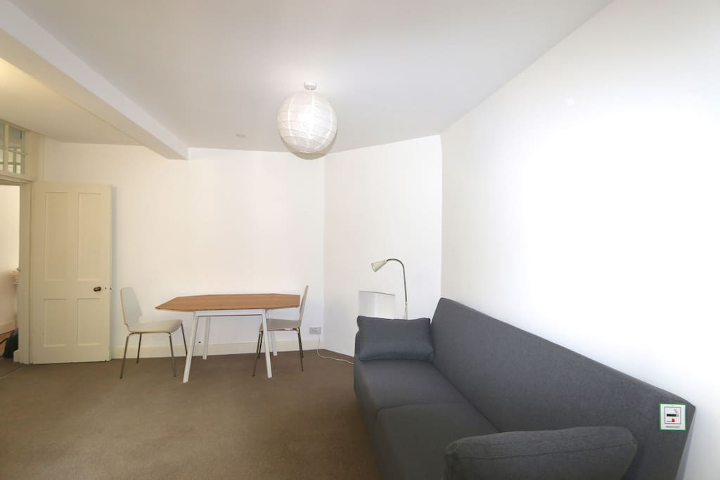 Open plan living room with sofa bed and extending dining table.