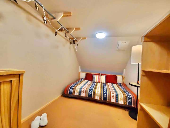 Lit double dans une chambre ouverte (sans porte), accessible avec échelles