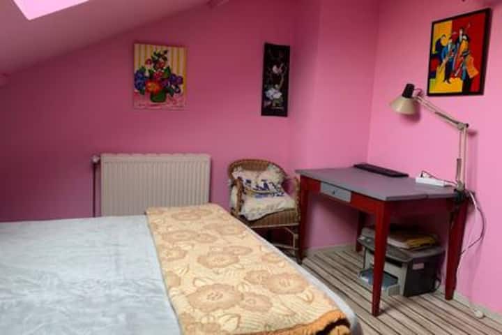 Розовата стая и бюрото ѝ за работа и почивка върху двойното легло и меките чаршафи