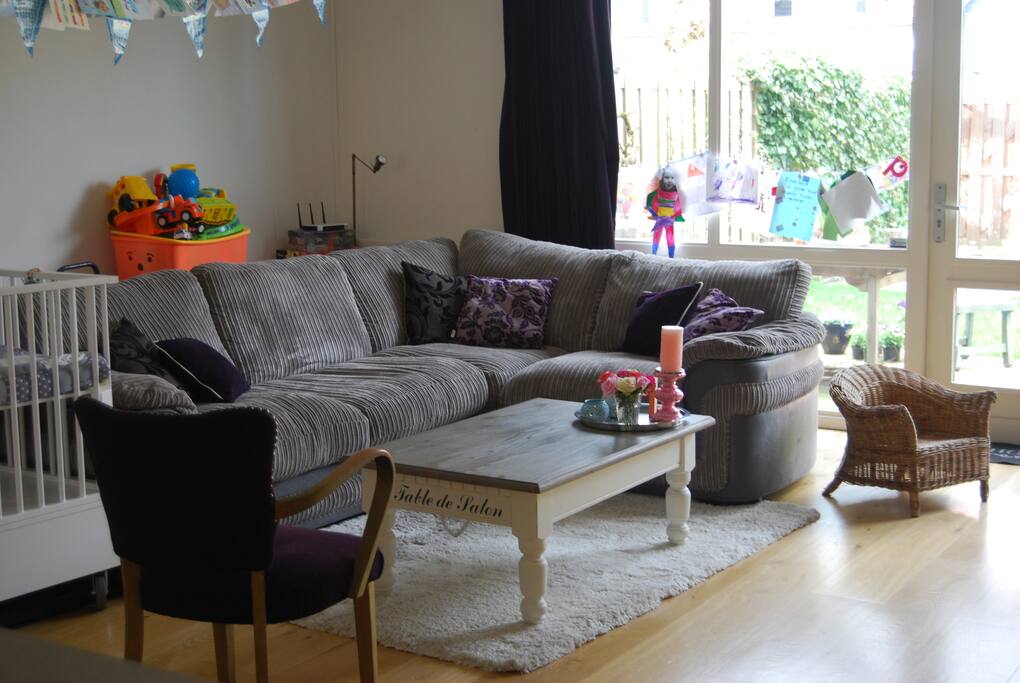Living room with a very big couch. And lots of toys behind the couch.