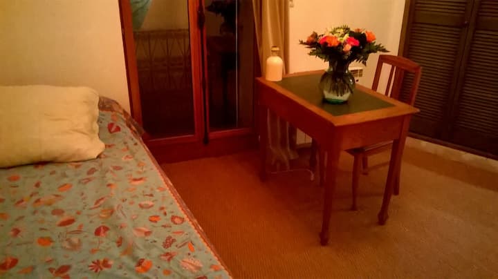 Një krevat tek, një tavolinë pune dhe hapësira e banjës që nuk e sheh në të djathtë