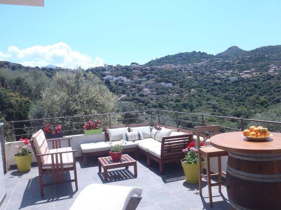 Le coin détente de la terrasse avec vue sur les collines d'oliviers, de chênes verts, et le village de Santa Réparata.
