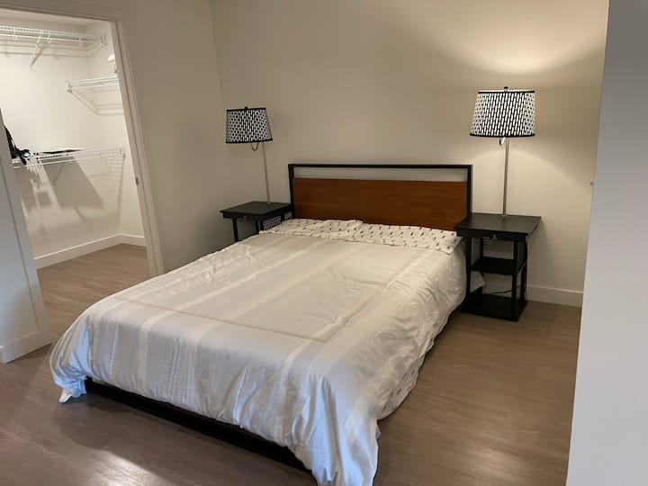 The bedroom has a comfortable queen sized bed with four pillows. The nightstands have USB ports for easy charging. Next to the bed is a large walk in closet with extra linens and plenty of space for clothing storage. 