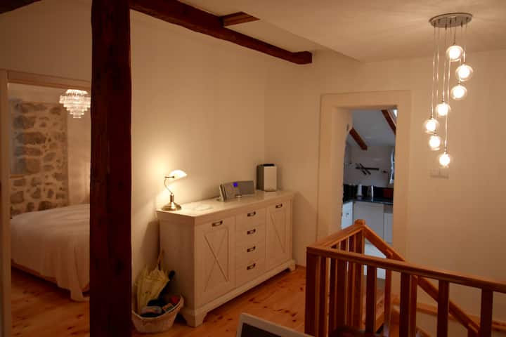 Upstairs hallway with chest of drawers and access to open plan living room, doors to bedroom and kitchen