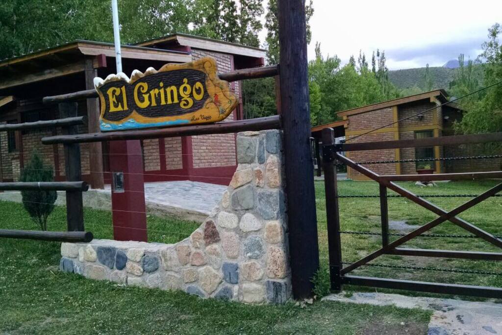 Tranquera principal de entrada y vista al espacio en general donde se ven los jardines y las dos cabañas
