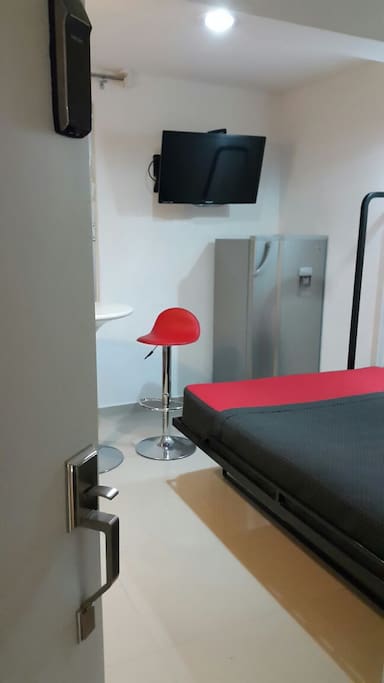 Habitación con cama matrimonial, pantalla, freego bar
