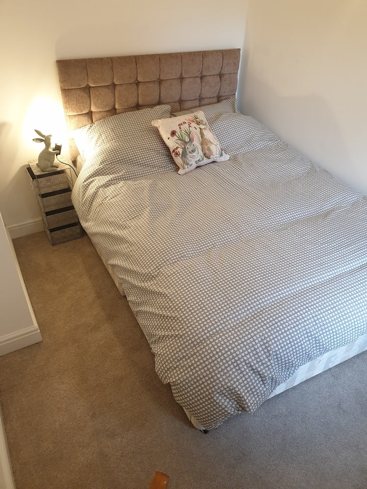A fresh clean bedroom features a double bed and chair.