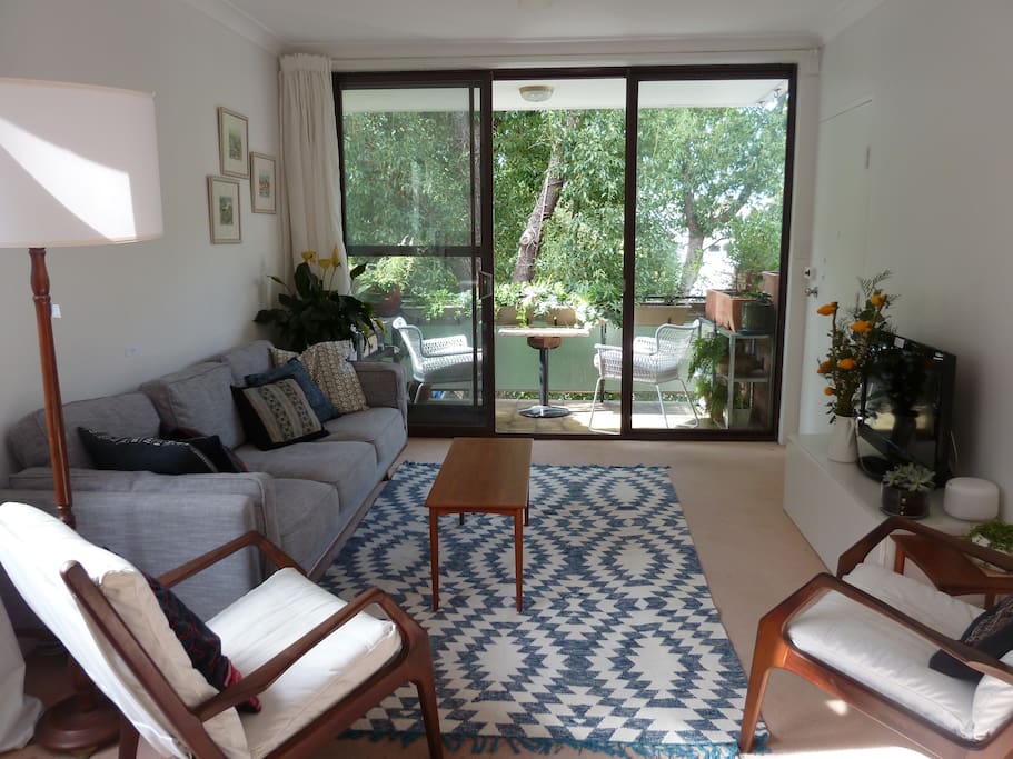 The lounge room leads onto a sunny and leafy balcony.