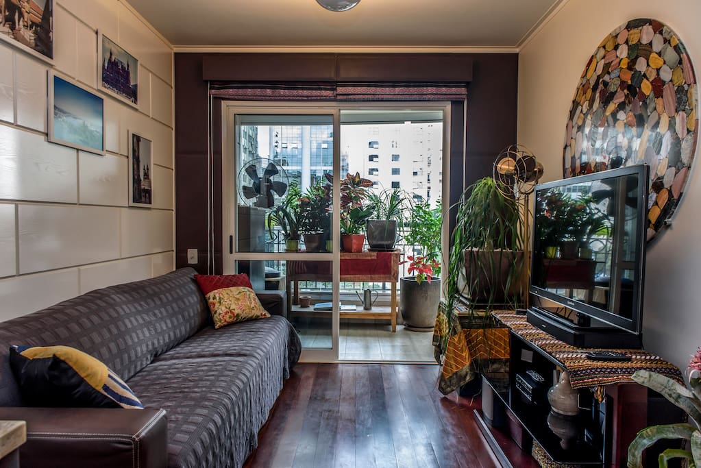 Living area, with 2.5 meter couch, glass-enclosed balcony, large-screen TV with Fiber Optic TV channels, Apple TV, and Bose Stereo sound.