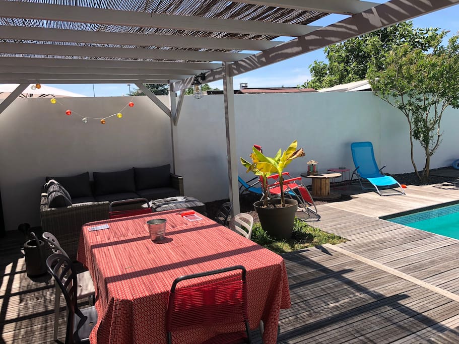 Terrasse ombragée avec du canisse équipée d’une table pour repas, canapé d’angle et transats