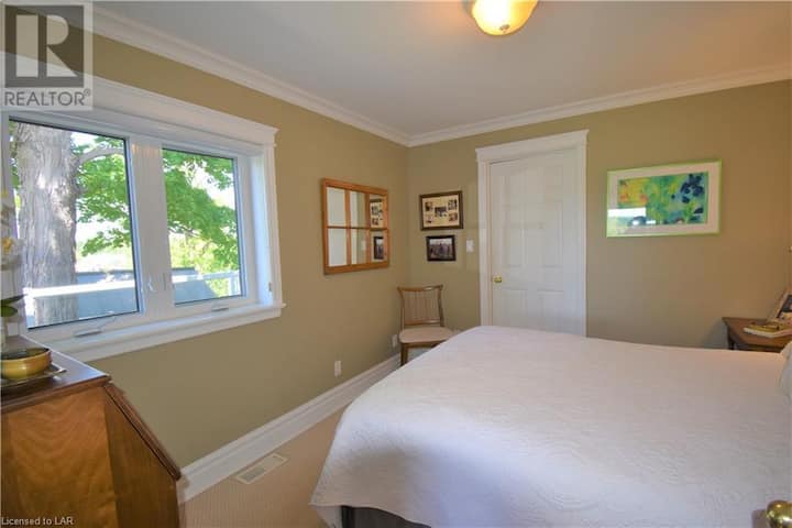 חדר שינה ראשי עם מיטת קווין סייז ודלת לחדר ארונות.